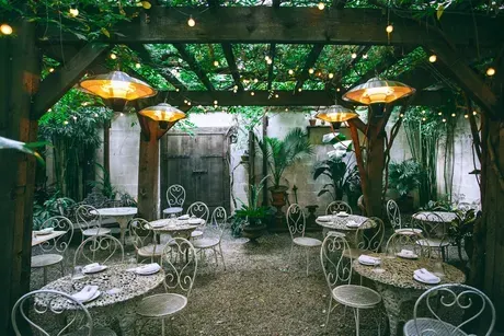 A restaurant with tables and chairs under a pergola.