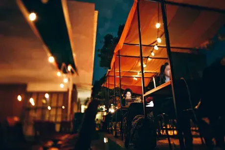 A blurry picture of people sitting at tables under a canopy at night.
