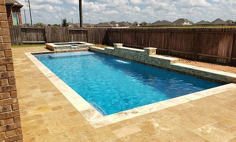 There is a large swimming pool in the backyard of a house.