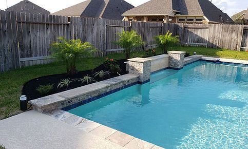 There is a large swimming pool in the backyard of a house.