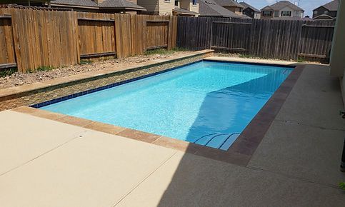 A large swimming pool surrounded by a wooden fence in a backyard.