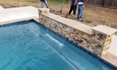 A couple of men are standing next to a swimming pool.