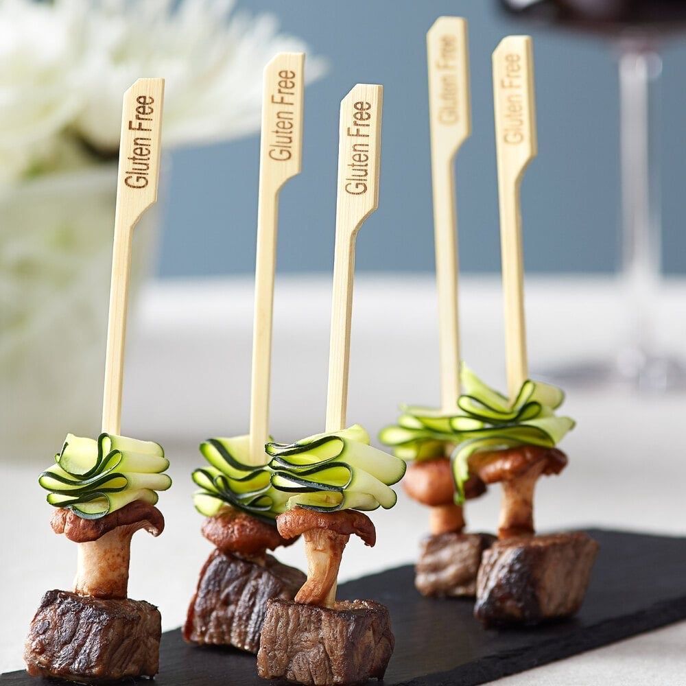 Appetizer skewers featuring seared beef, a mushroom, and cucumber ribbons, labeled with bamboo 