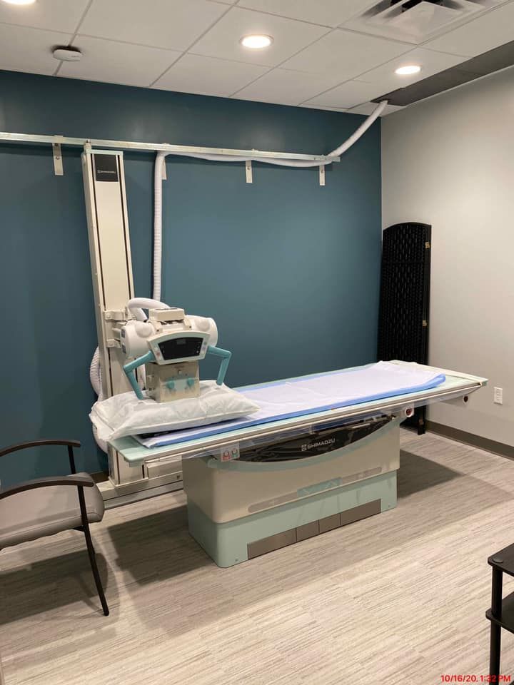 X-ray room with examination table and imaging equipment. Blue wall.