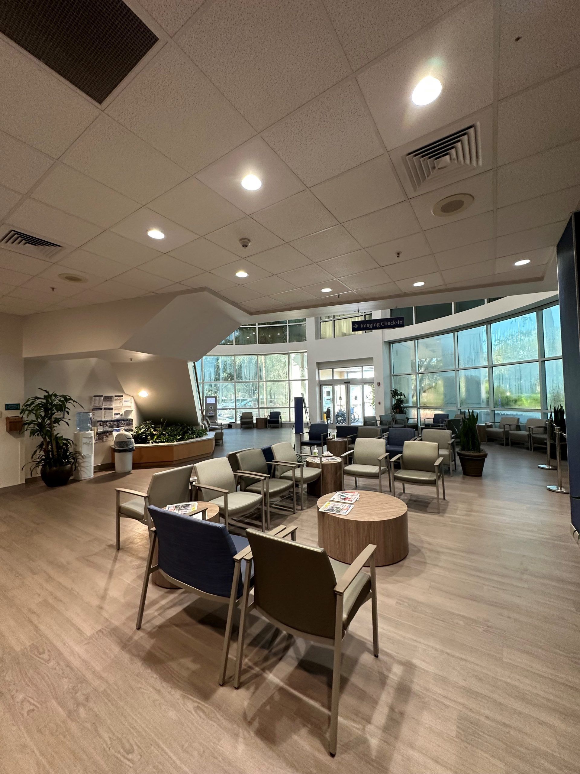 Waiting area with chairs, coffee tables, and large windows. Interior view.