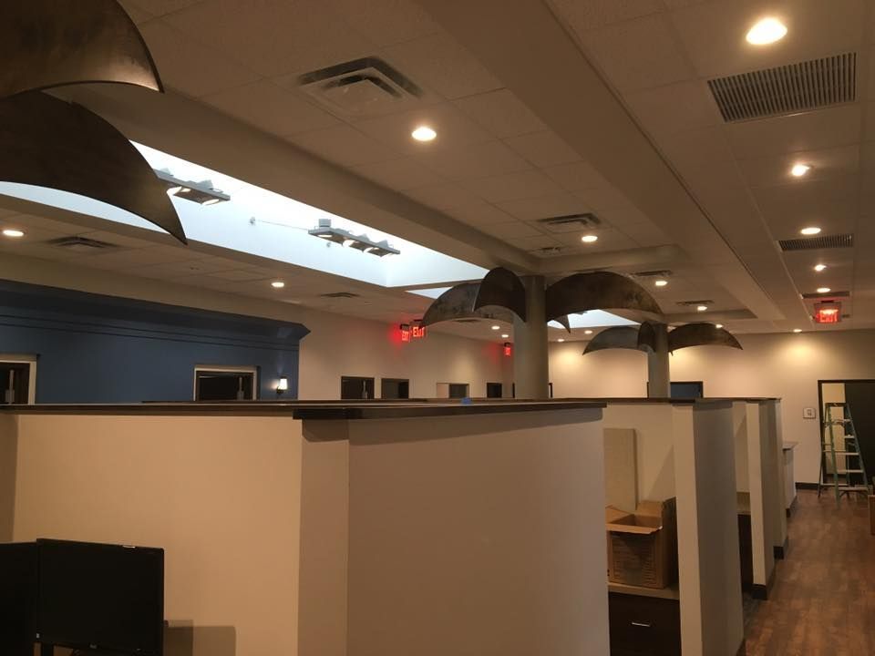 Office interior with cubicles, recessed lighting, and decorative palm tree structures on the ceiling.