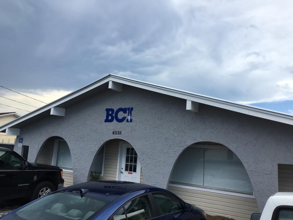 Gray stucco building with arched windows, blue logo 