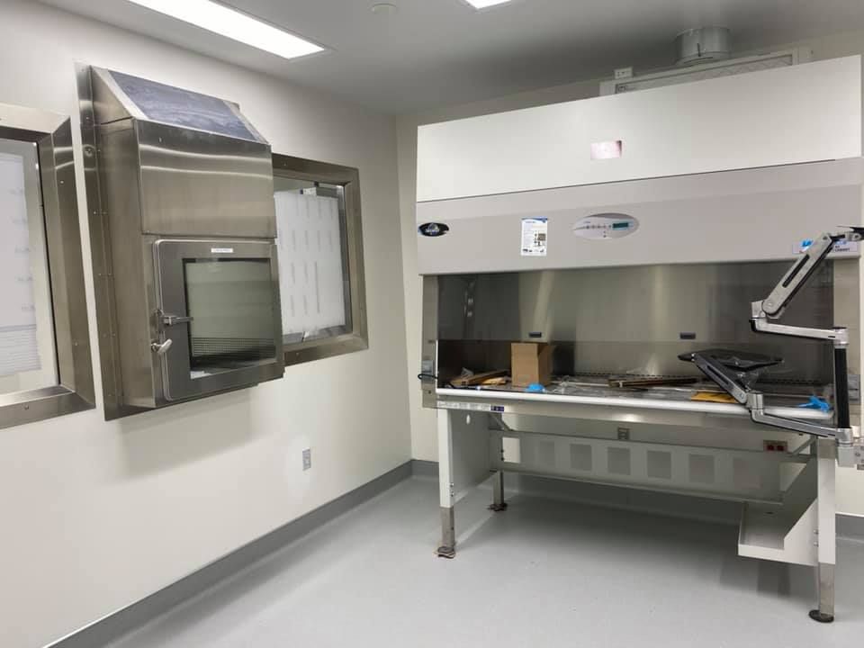 Cleanroom with a stainless steel cabinet on the wall and a lab hood. White walls and floor.