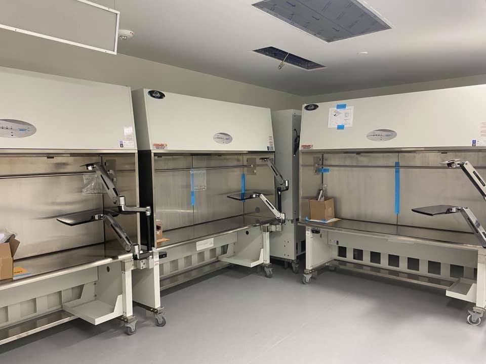 Two stainless steel laboratory hoods in a clean room, each with a work surface and attached lighting.