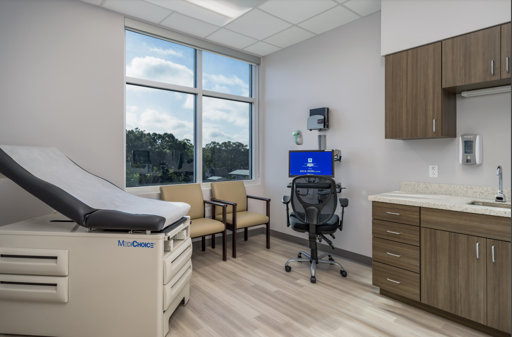 Examination room with exam table, chairs, window with a view, and medical equipment.