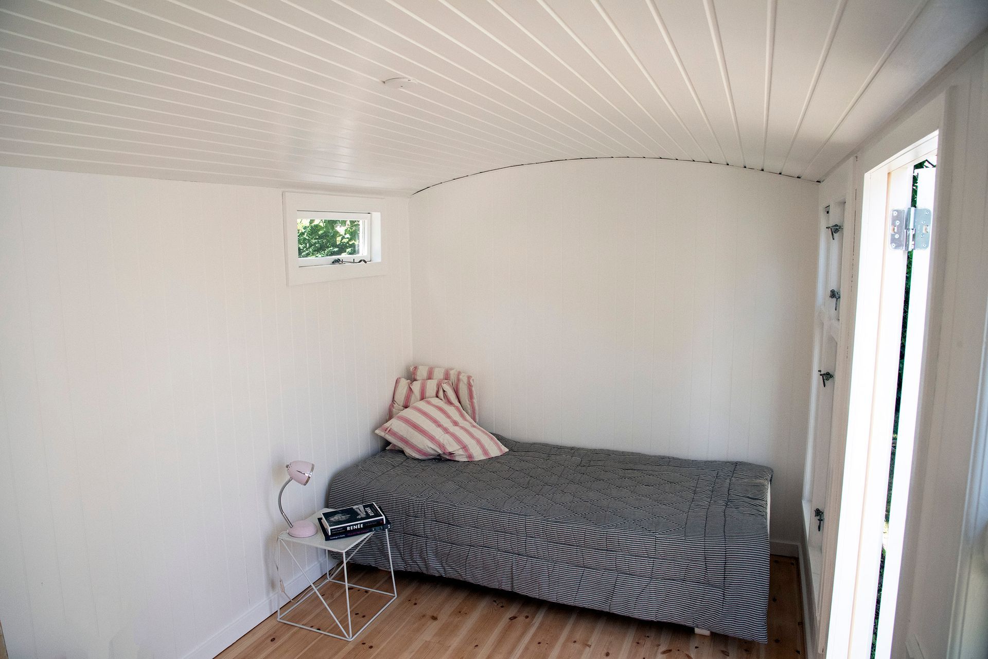 Indretning af en skurvogn som soveværelse med en seng og natbord.