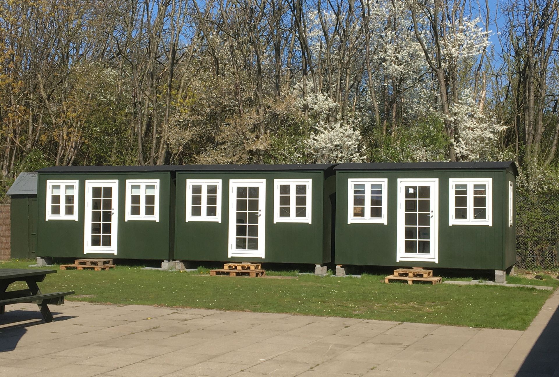 En række grønne skurvogne med hvide vinduer og døre side om side.