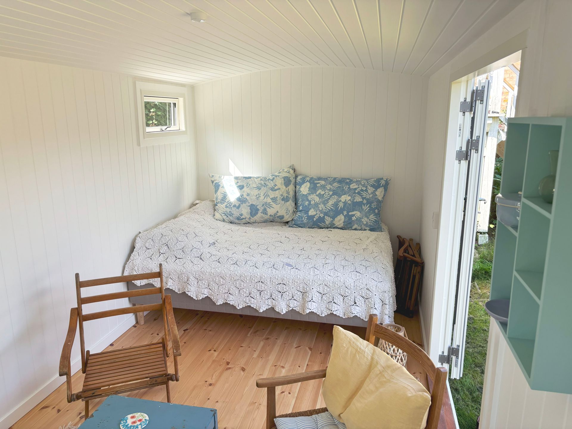 Indretning af en skurvogn som gæsteværelse med en seng og stole.