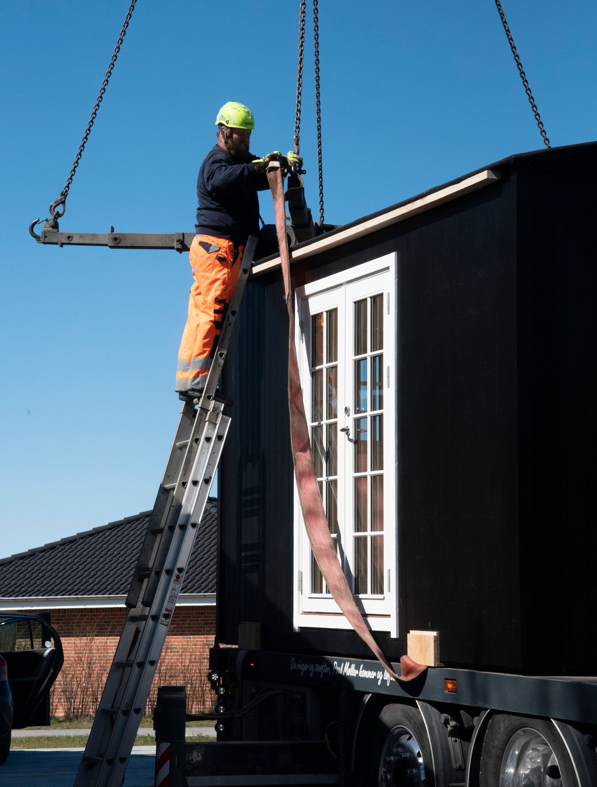 En mand på en stige arbejder på en skurvogn.