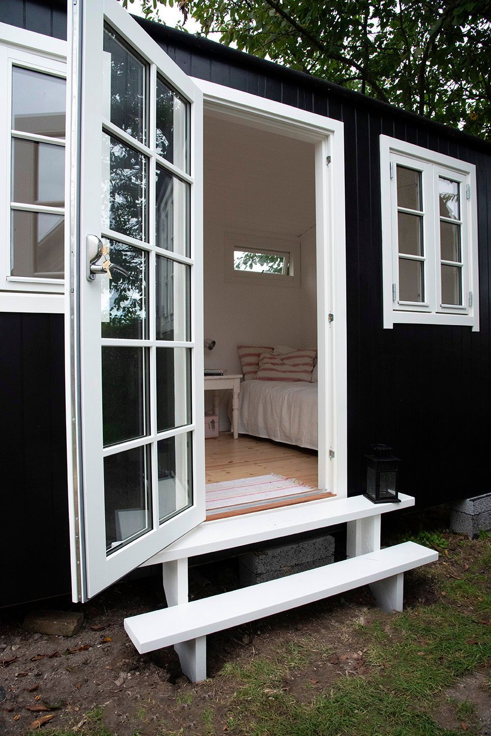 Et sort skur med en hvid bænk foran.