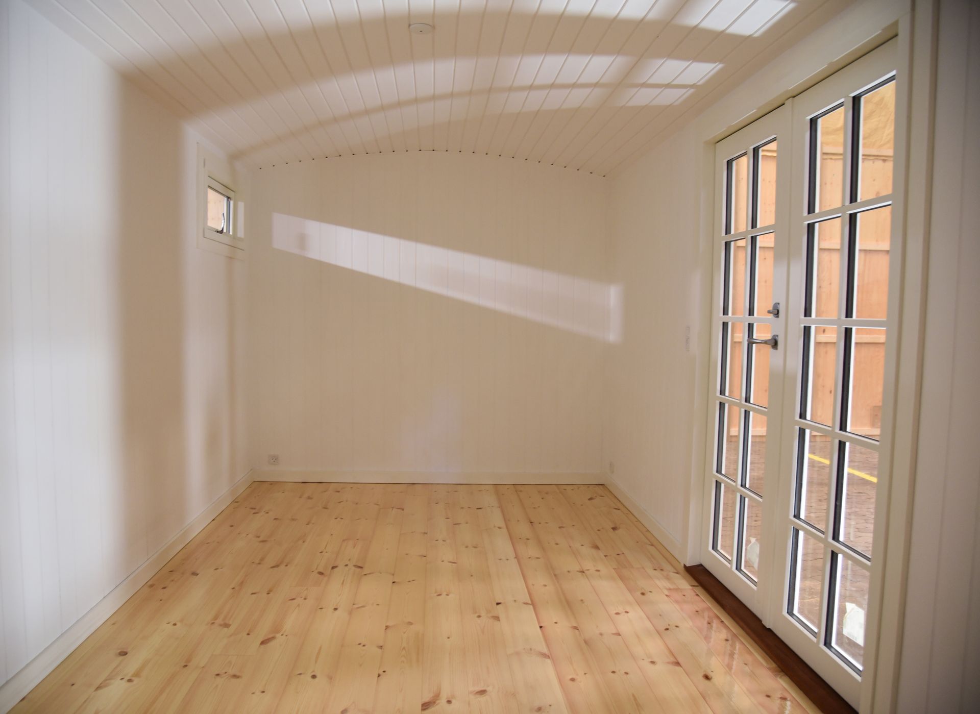 Et tomt rum med trægulve og hvide vægge inden i en skurvogn