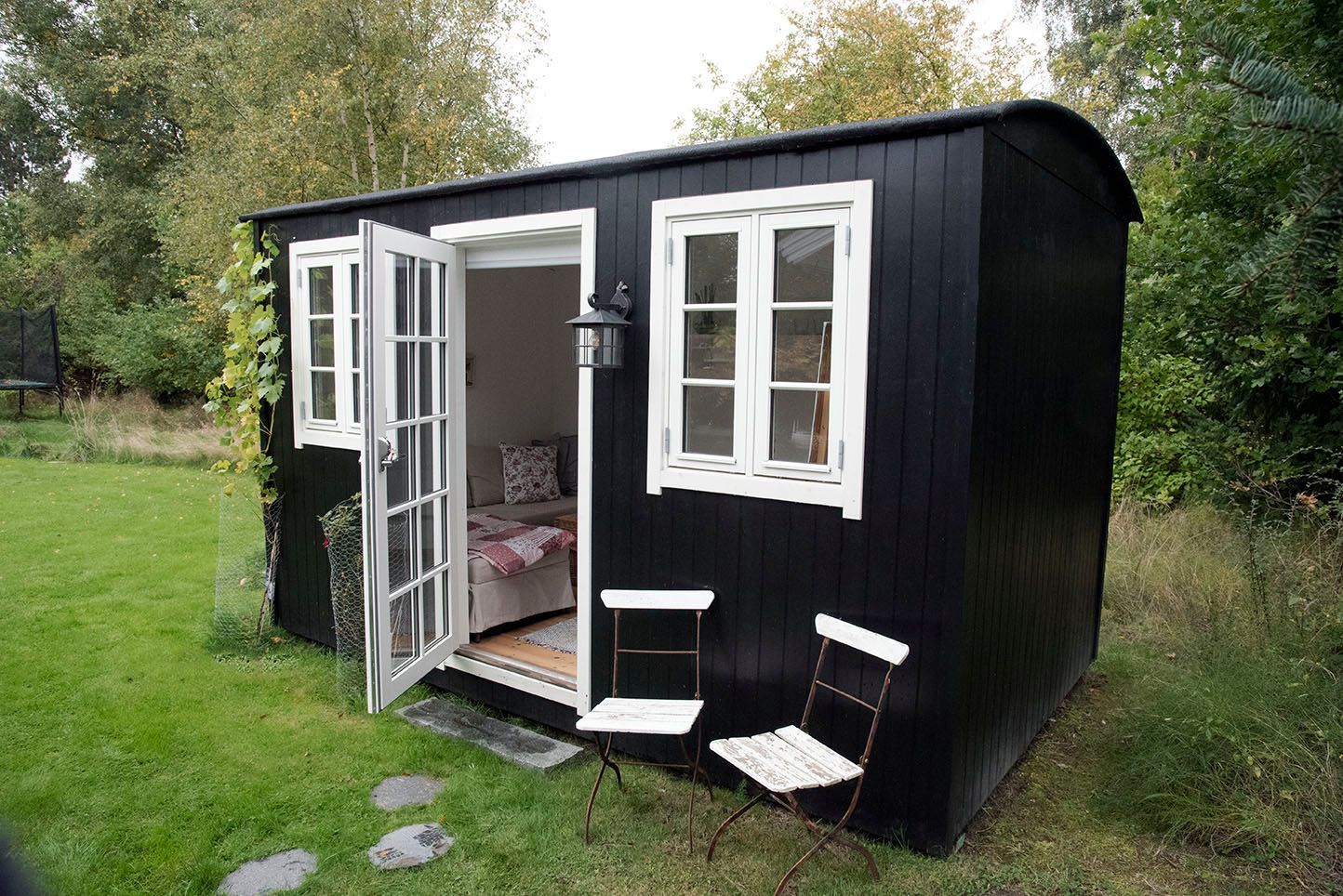 Et sort skur med hvide vinduer og en åben dør.