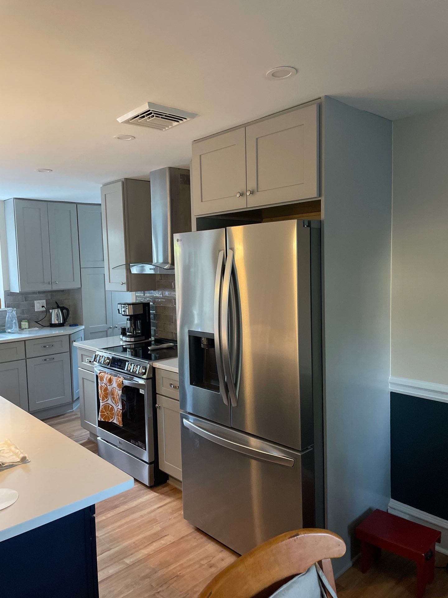 A kitchen with gray cabinets, stainless steel appliances, and wood floors.