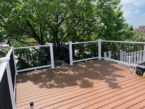 Covered outdoor deck with furniture, fireplace, and TV.