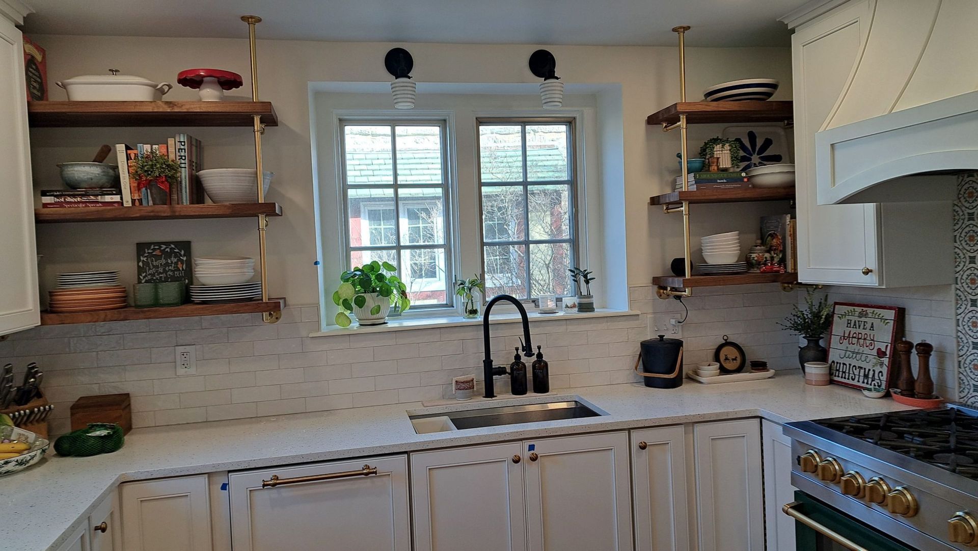 Bright kitchen with white cabinets, marble backsplash, open shelves, window, and sink.