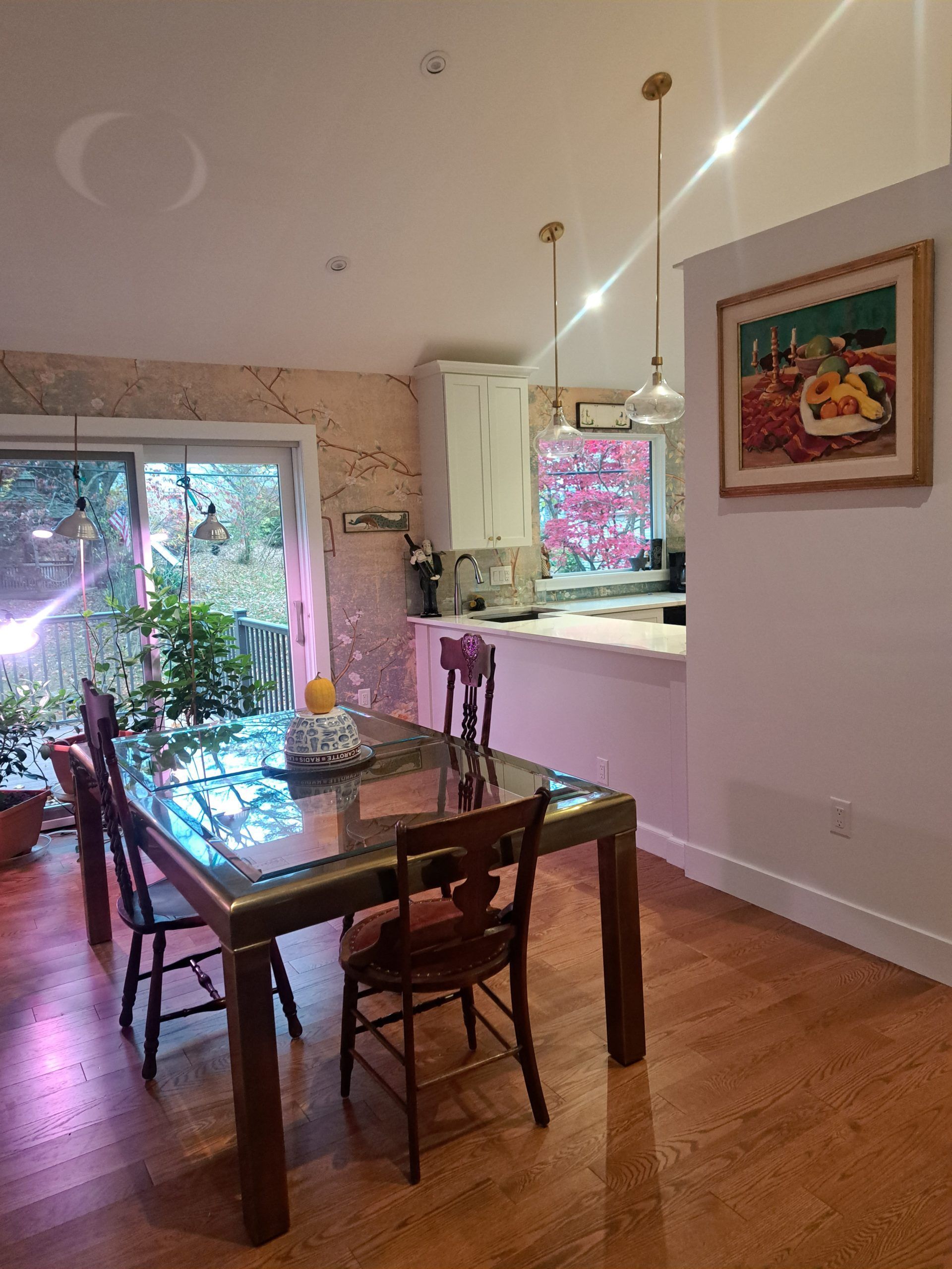 Dining room with table, chairs, kitchen, artwork, and sliding door to a patio.