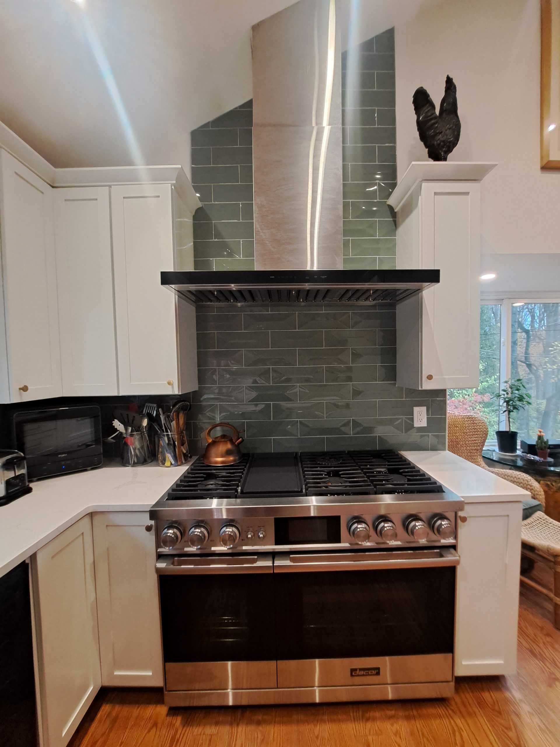 Kitchen with stainless steel range, hood, white cabinets, and green tile backsplash.