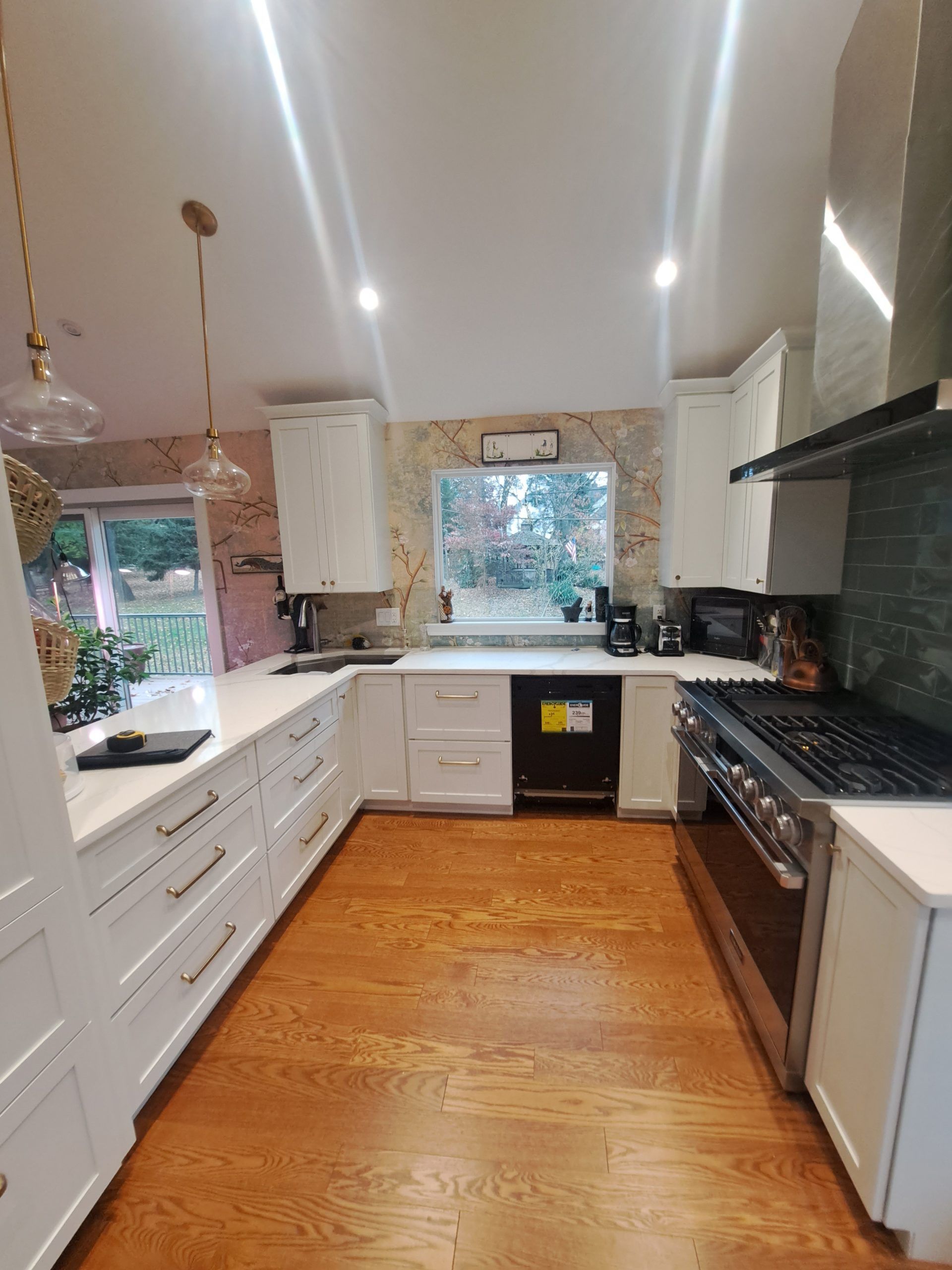 U-shaped kitchen with white cabinets, light wood floor, and stainless steel appliances.