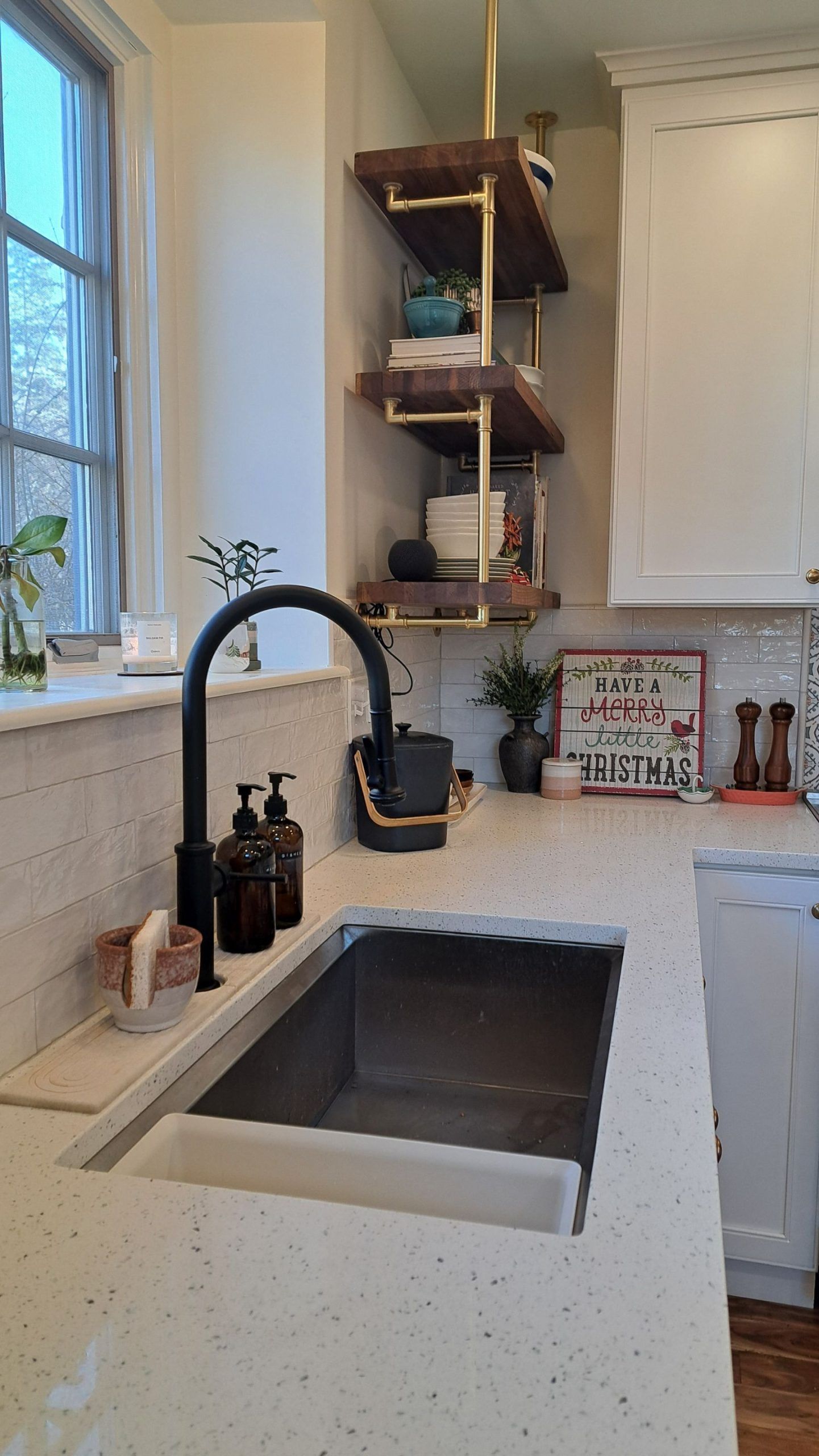 Kitchen with black faucet, concrete sink, open shelves with dishes, and white cabinets.