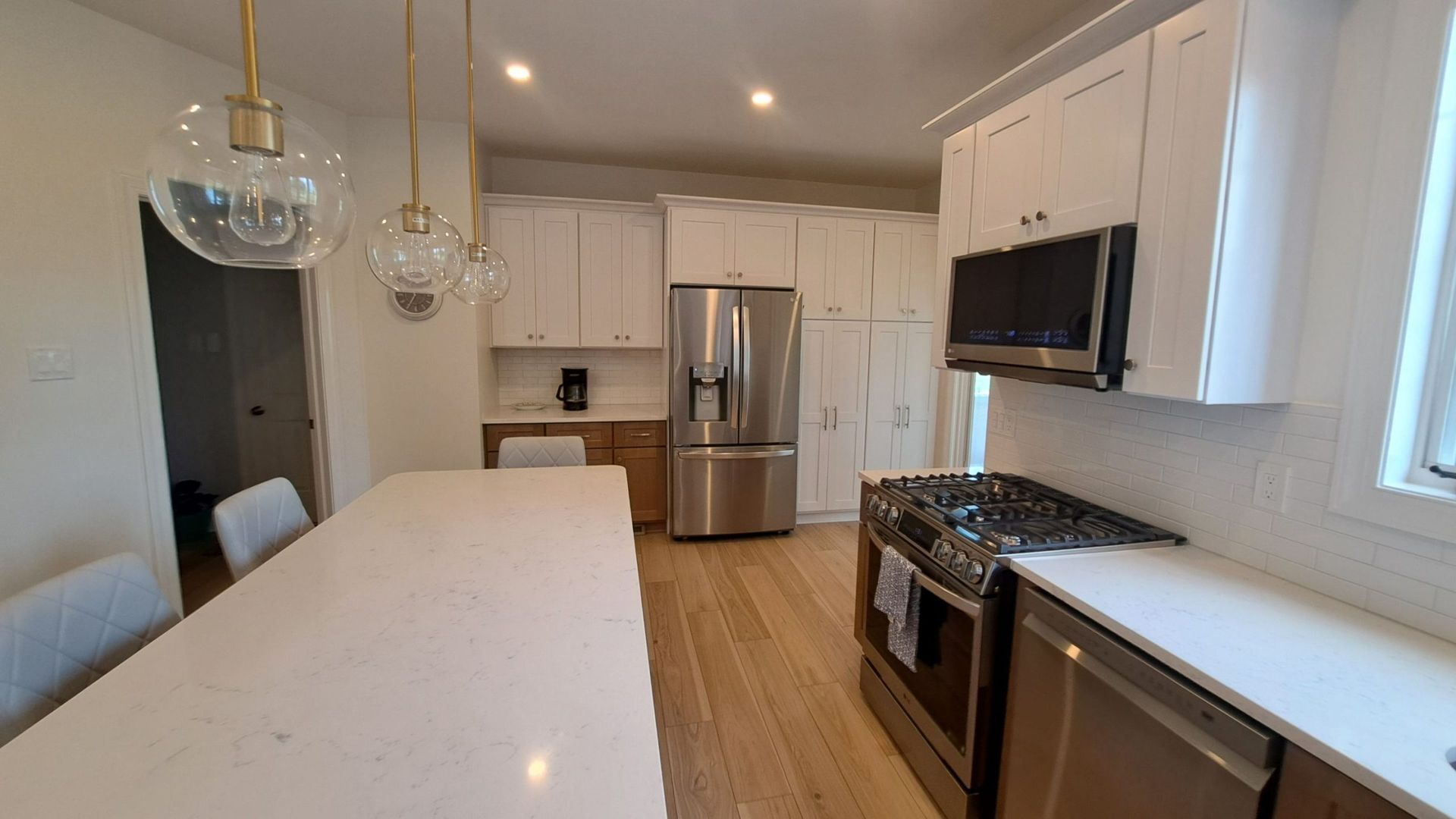 Modern kitchen with white cabinets, stainless steel appliances, and a quartz countertop island.