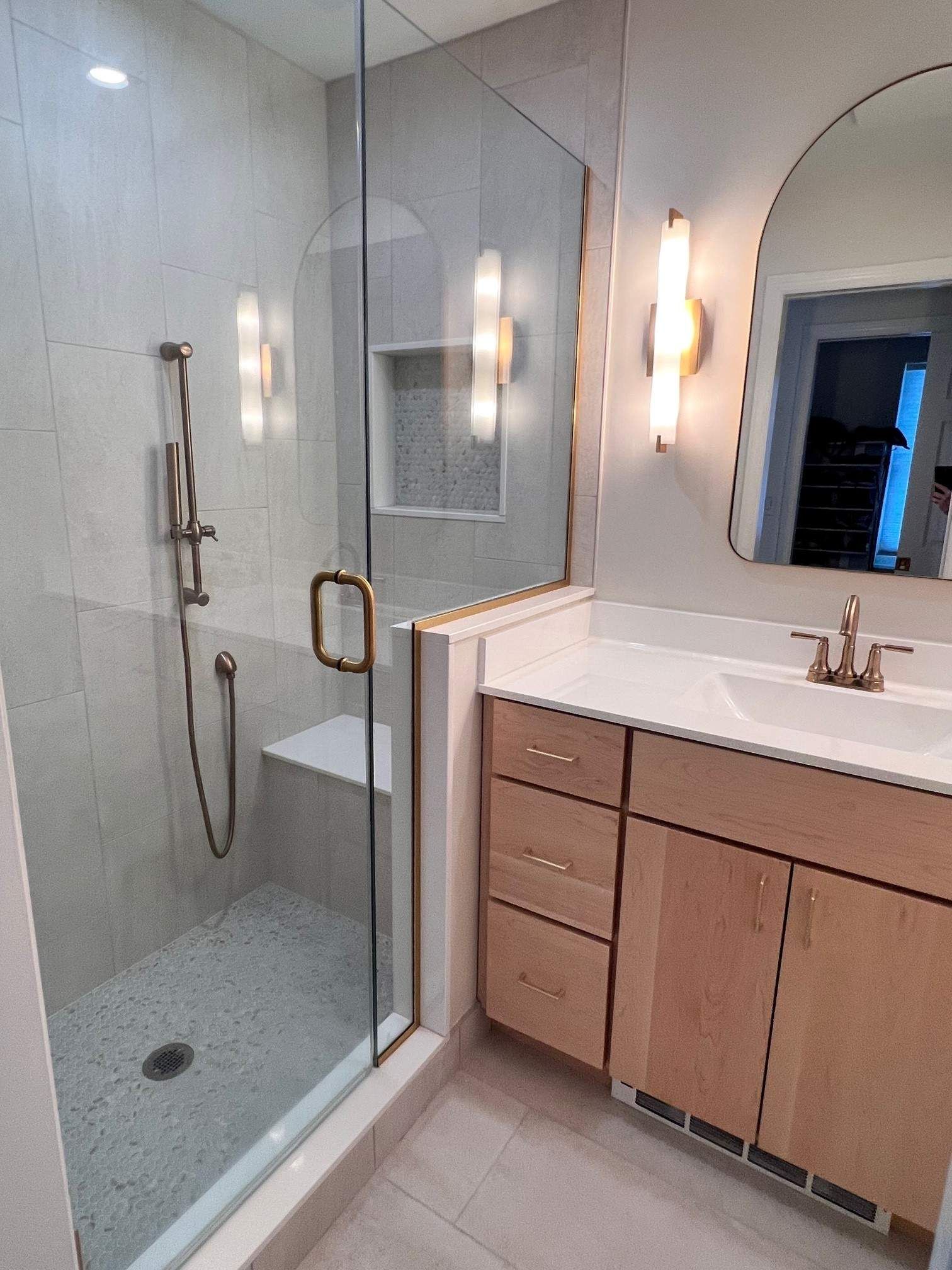 Modern bathroom with a glass shower, vanity, and gold accents.