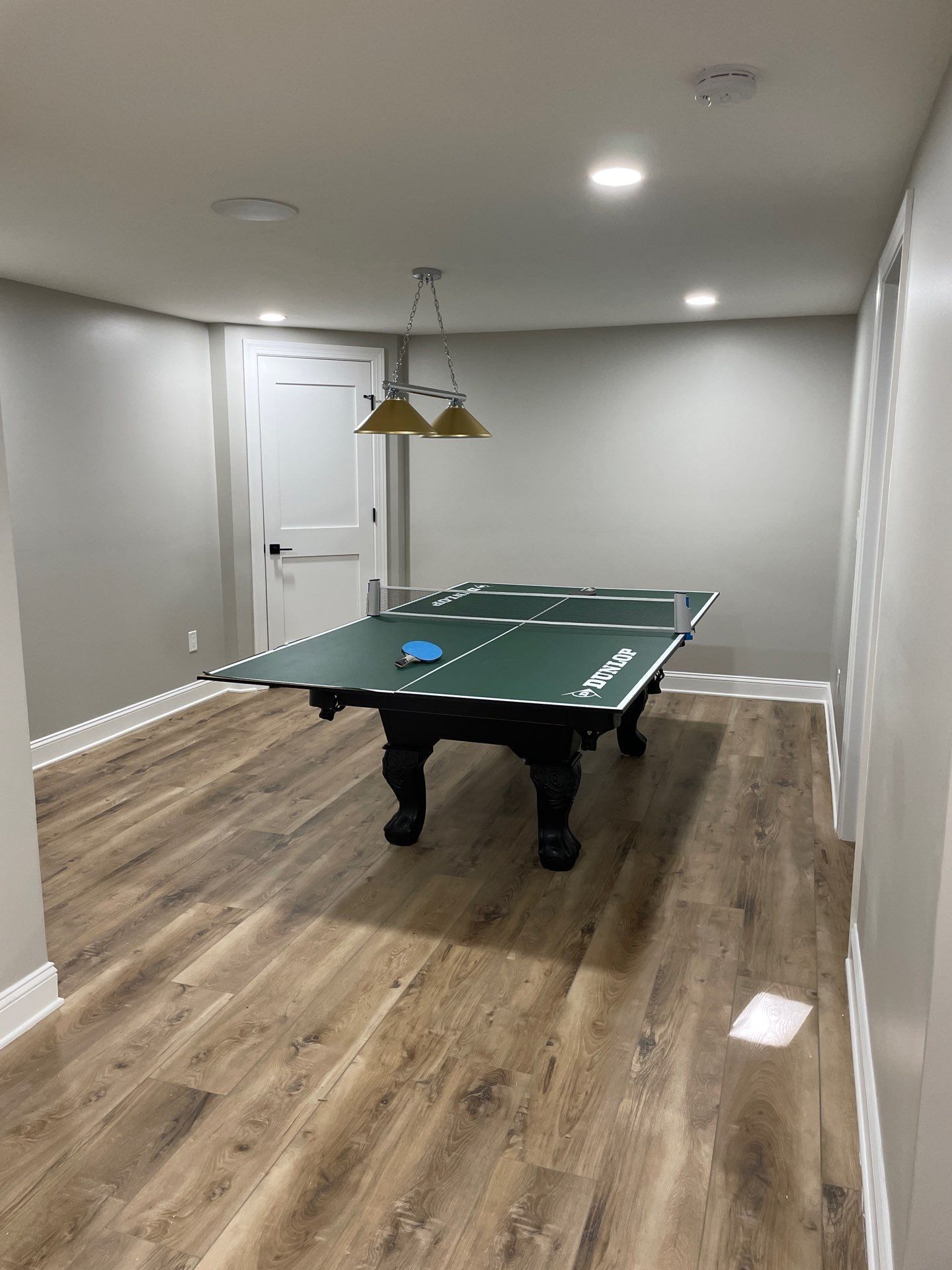Ping pong table in a room with hardwood floors and recessed lighting.