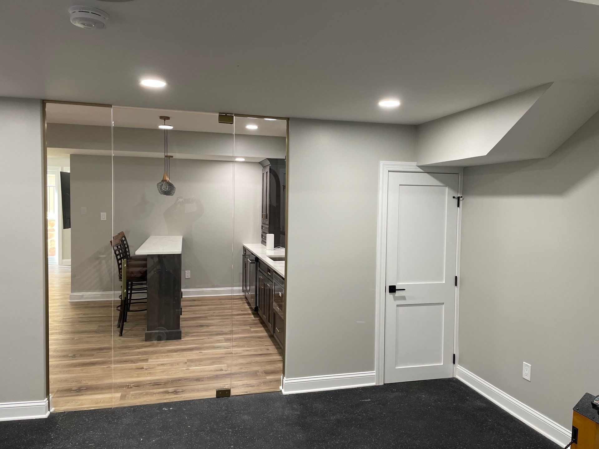 Open-concept kitchen and living room with large windows, island with stools, white sofa, blue armchairs, and wood floors.