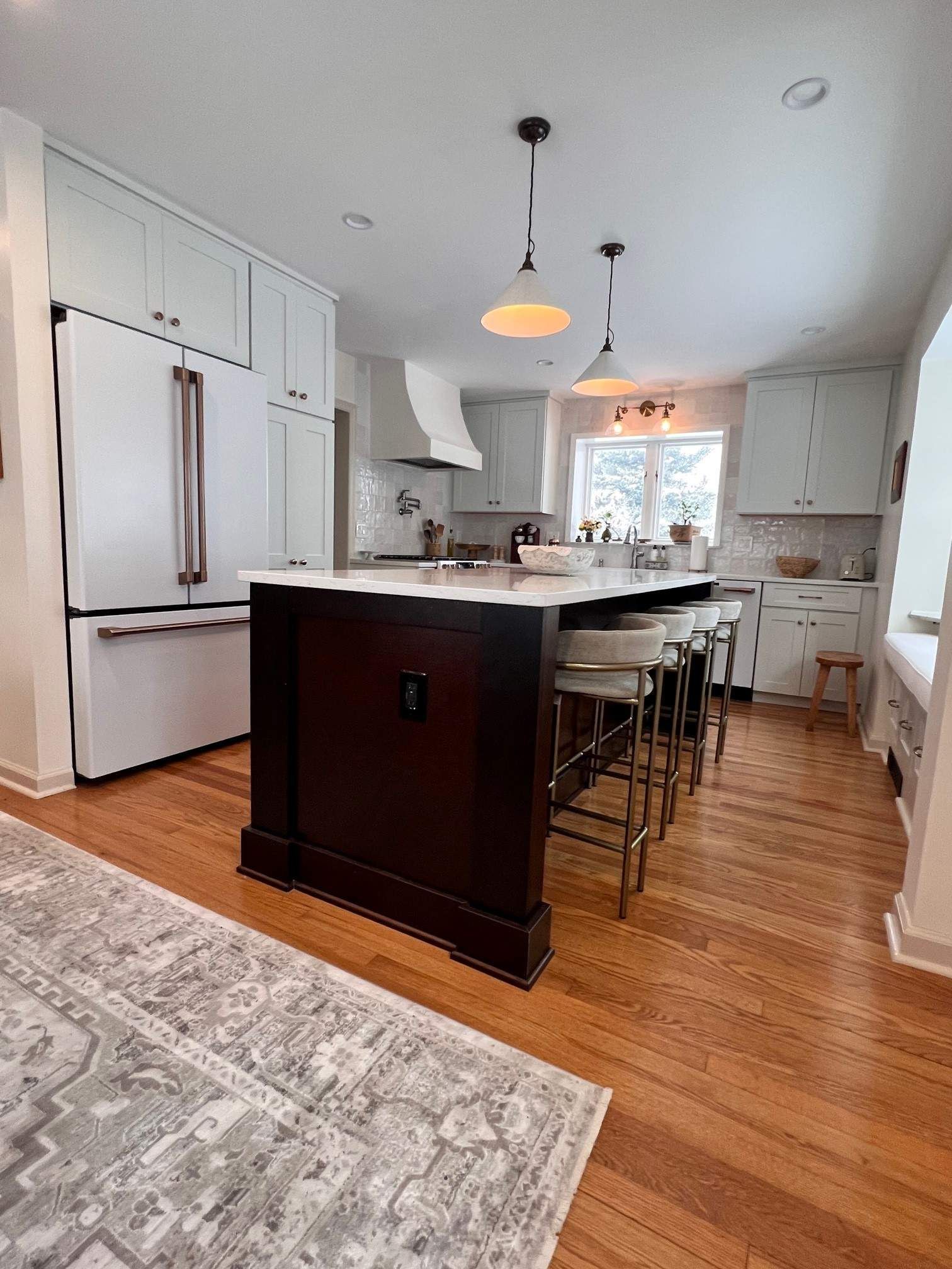 Kitchen with white cabinets, dark wood island, and wood floors.