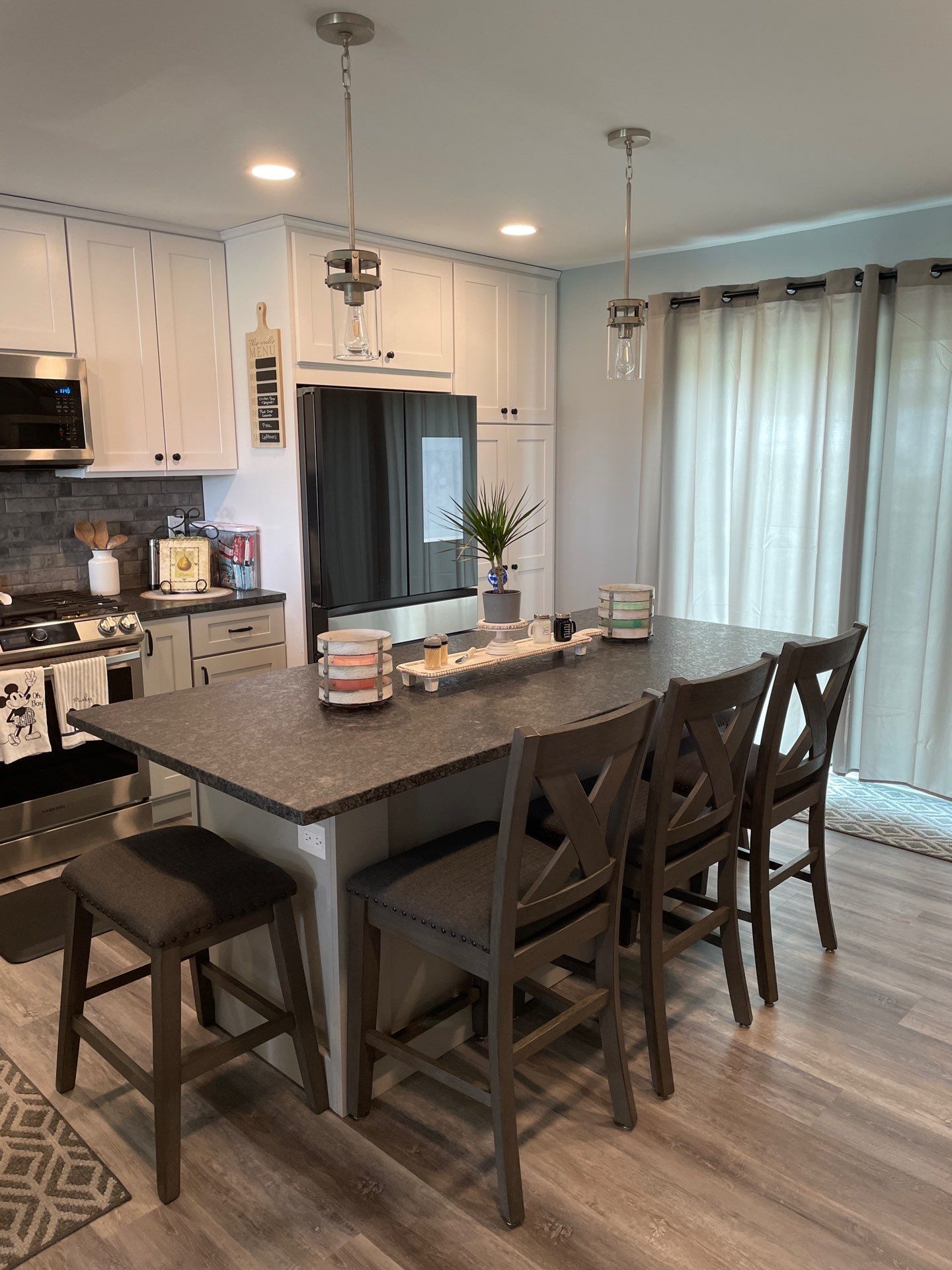 Modern kitchen with island, gray countertop, white cabinets, and bar stools.