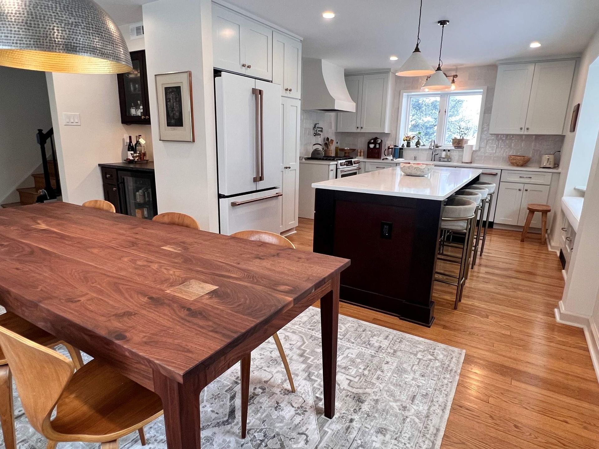 Kitchen with dark wood dining table and island, white cabinets, and stainless steel appliances.