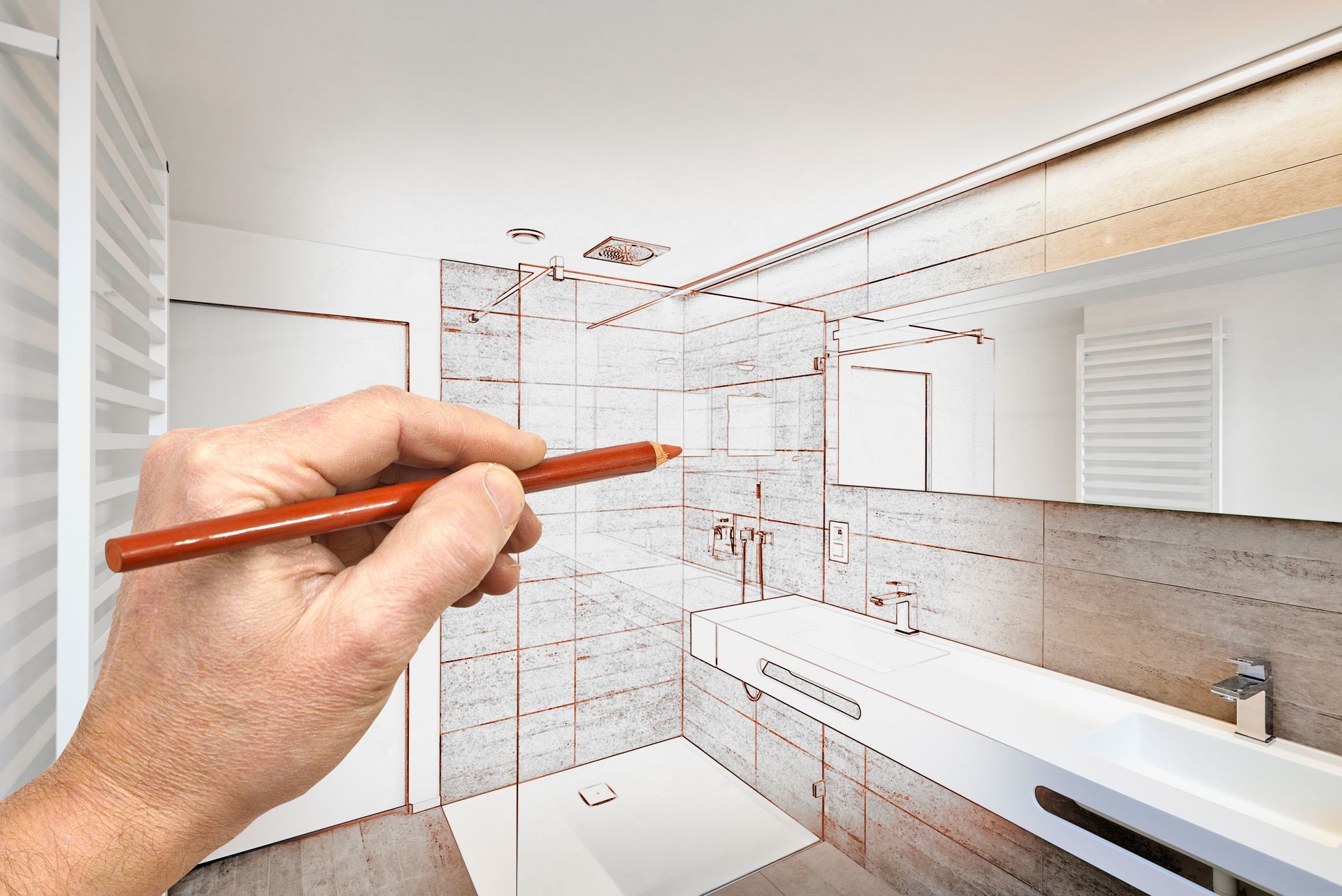Hand holding pencil sketching bathroom remodel design over completed interior scene.