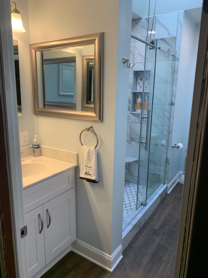 Bathroom interior with white vanity, mirror, and glass shower.