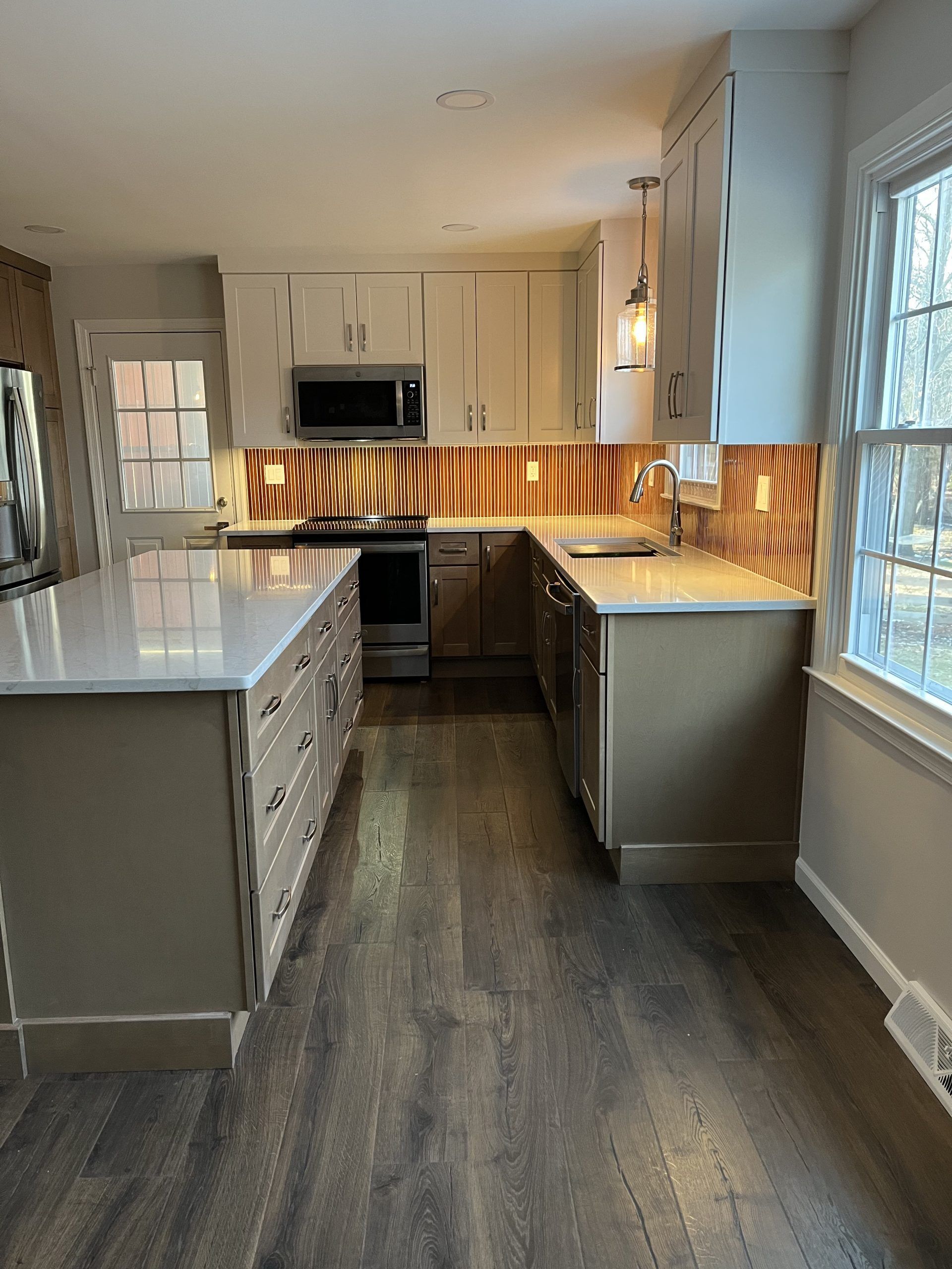 Modern kitchen with beige cabinets, a brown island, and wood floors.
