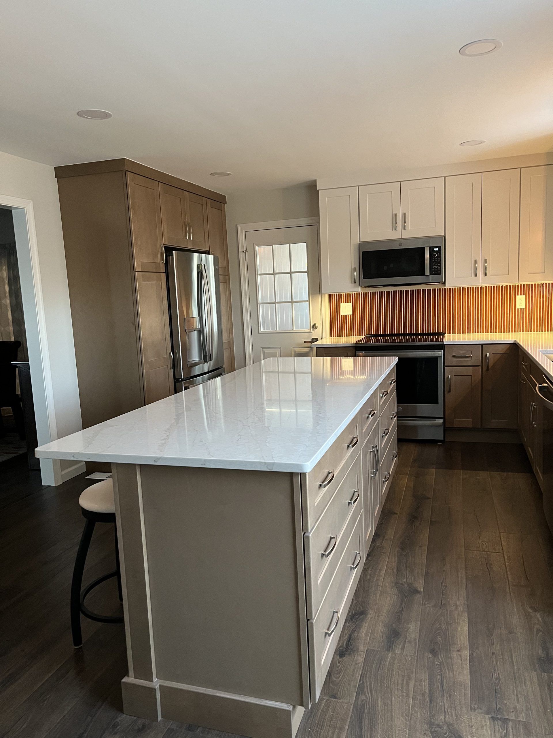 Modern kitchen with a large island, stainless steel appliances, and wood flooring.