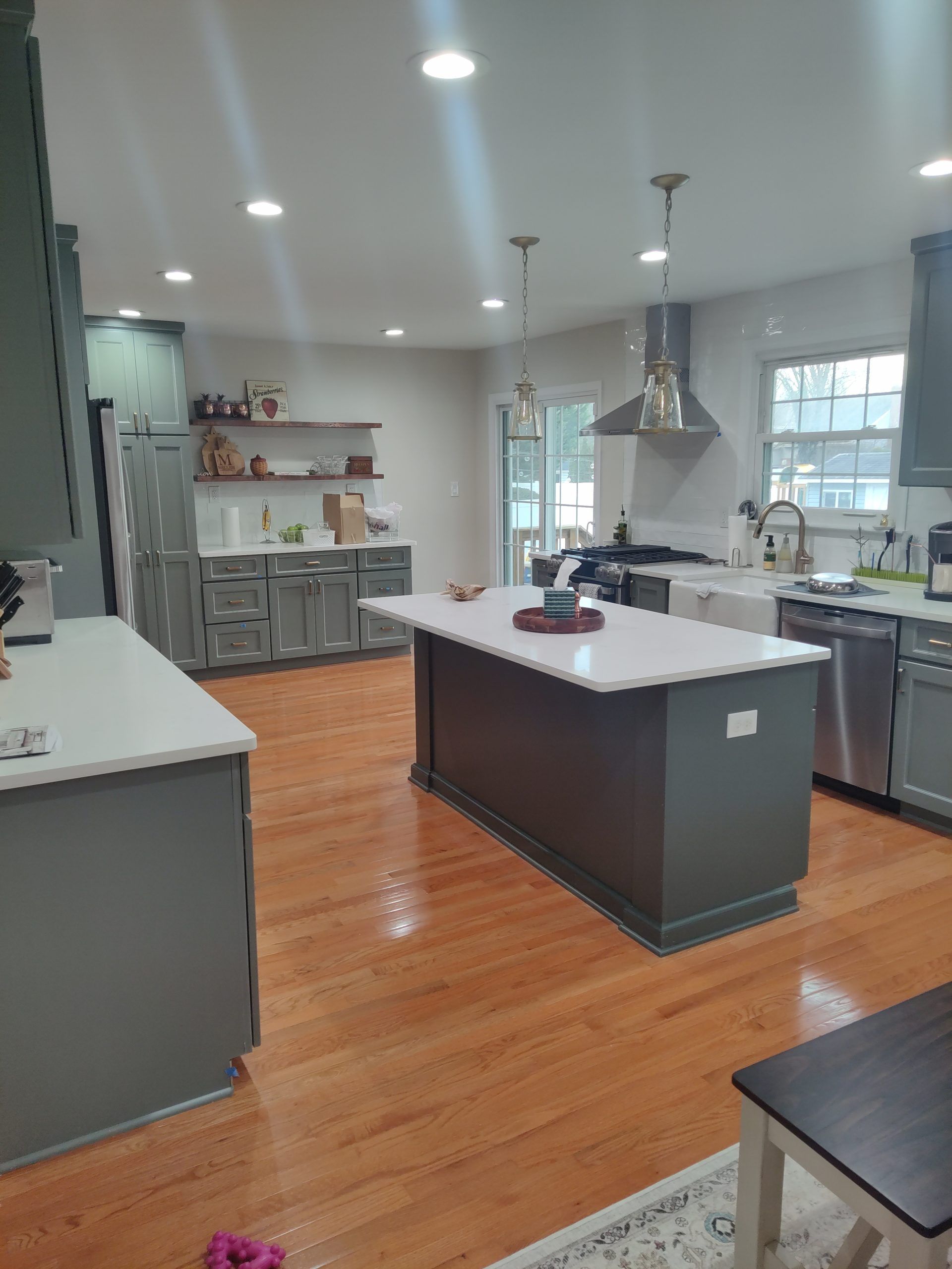 Kitchen with gray cabinets, white countertops, wooden floors, and an island.