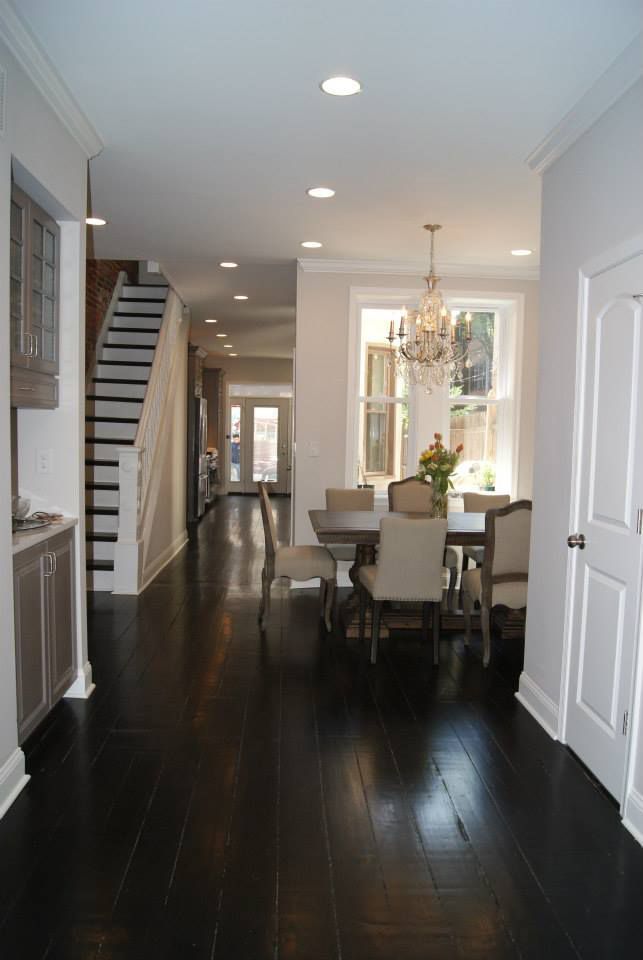 Long, narrow dining room with dark wood floors, white trim, and a chandelier above a table.