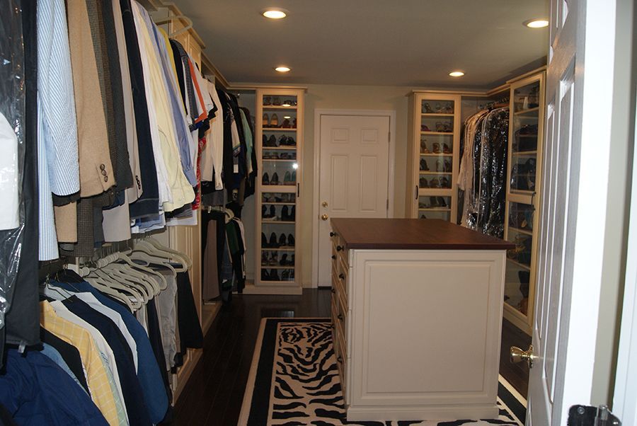 Walk-in closet with hanging clothes, shoe shelves, an island, and a zebra rug.