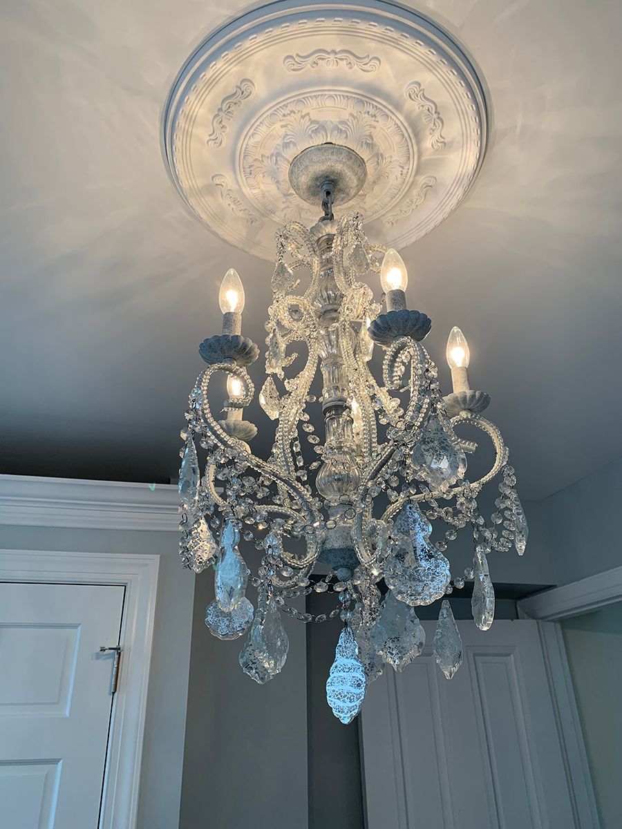 Crystal chandelier hanging from a white ceiling with a decorative ceiling medallion.