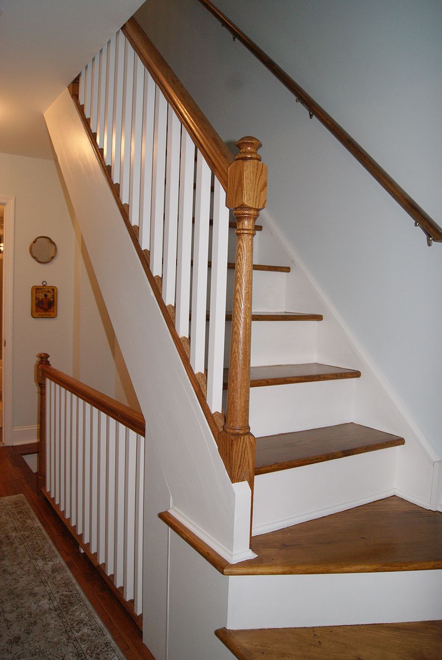 Wooden staircase with white spindles, brown banister and steps, and a white base.