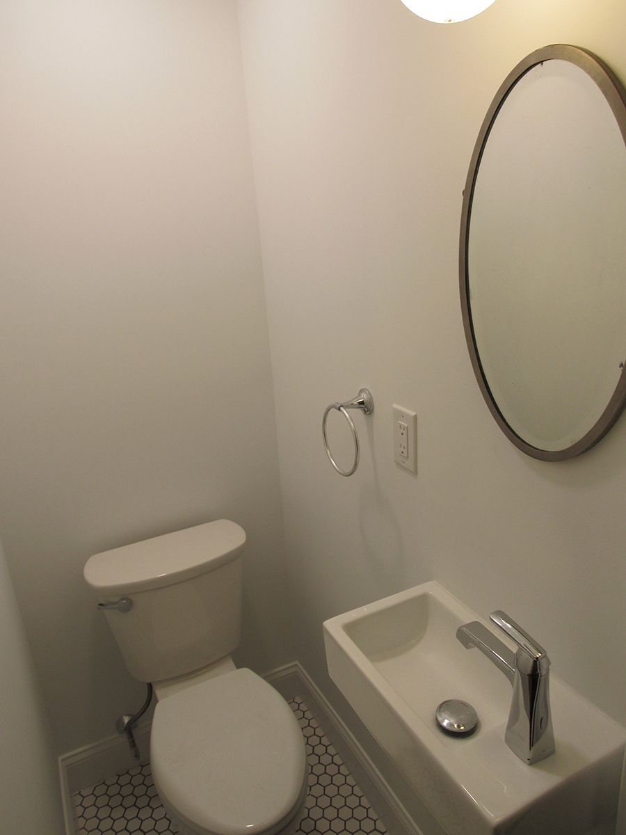 Small bathroom with toilet, sink, mirror, and light fixture.