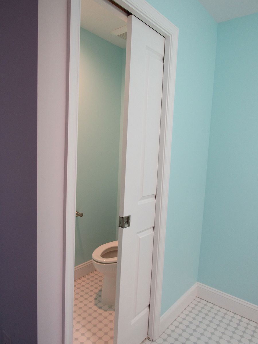 White pocket door partially open to a small bathroom. Blue and white walls. Toilet visible.