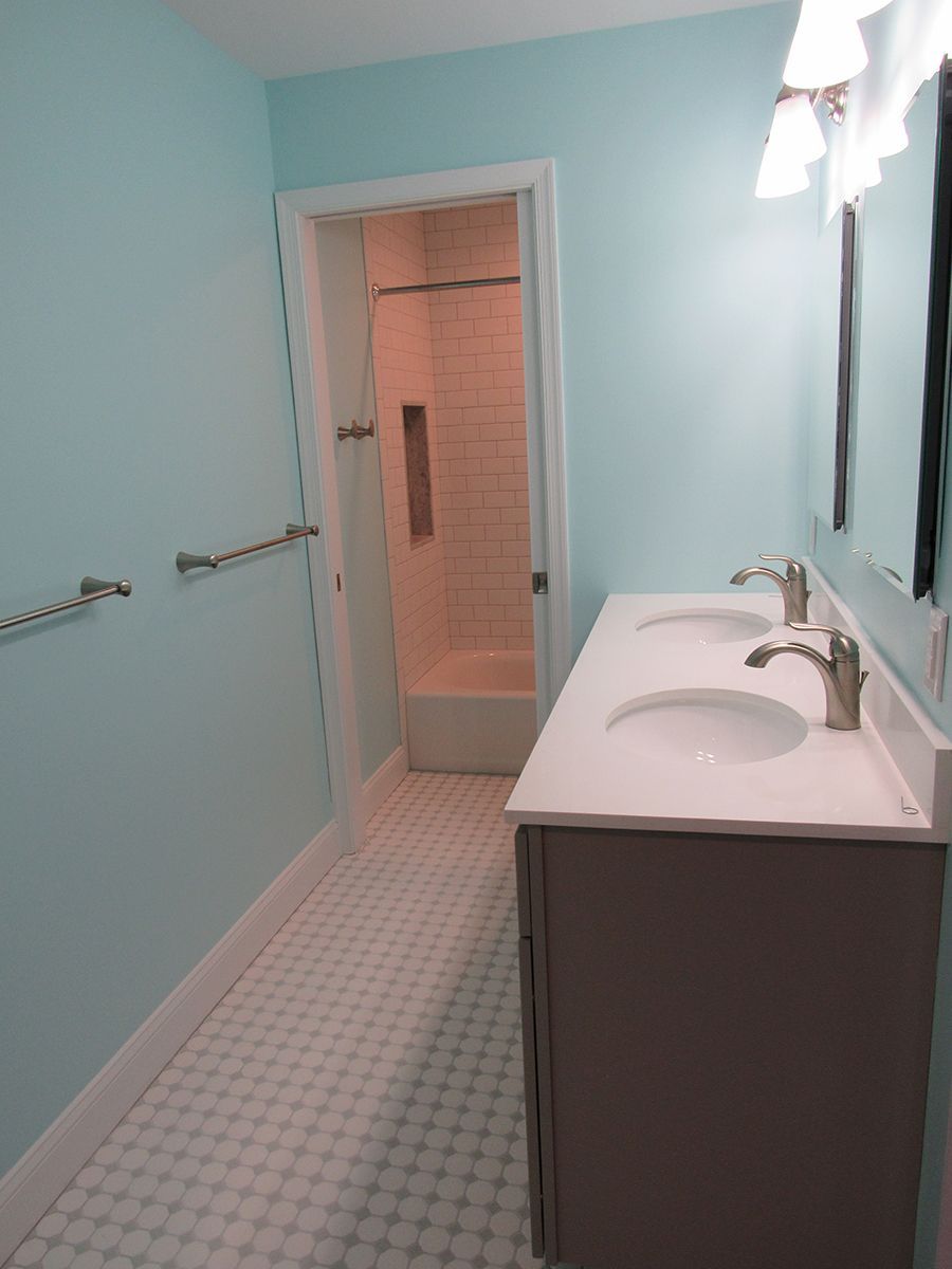 Bathroom with blue walls, double vanity, shower, and white tile floor.
