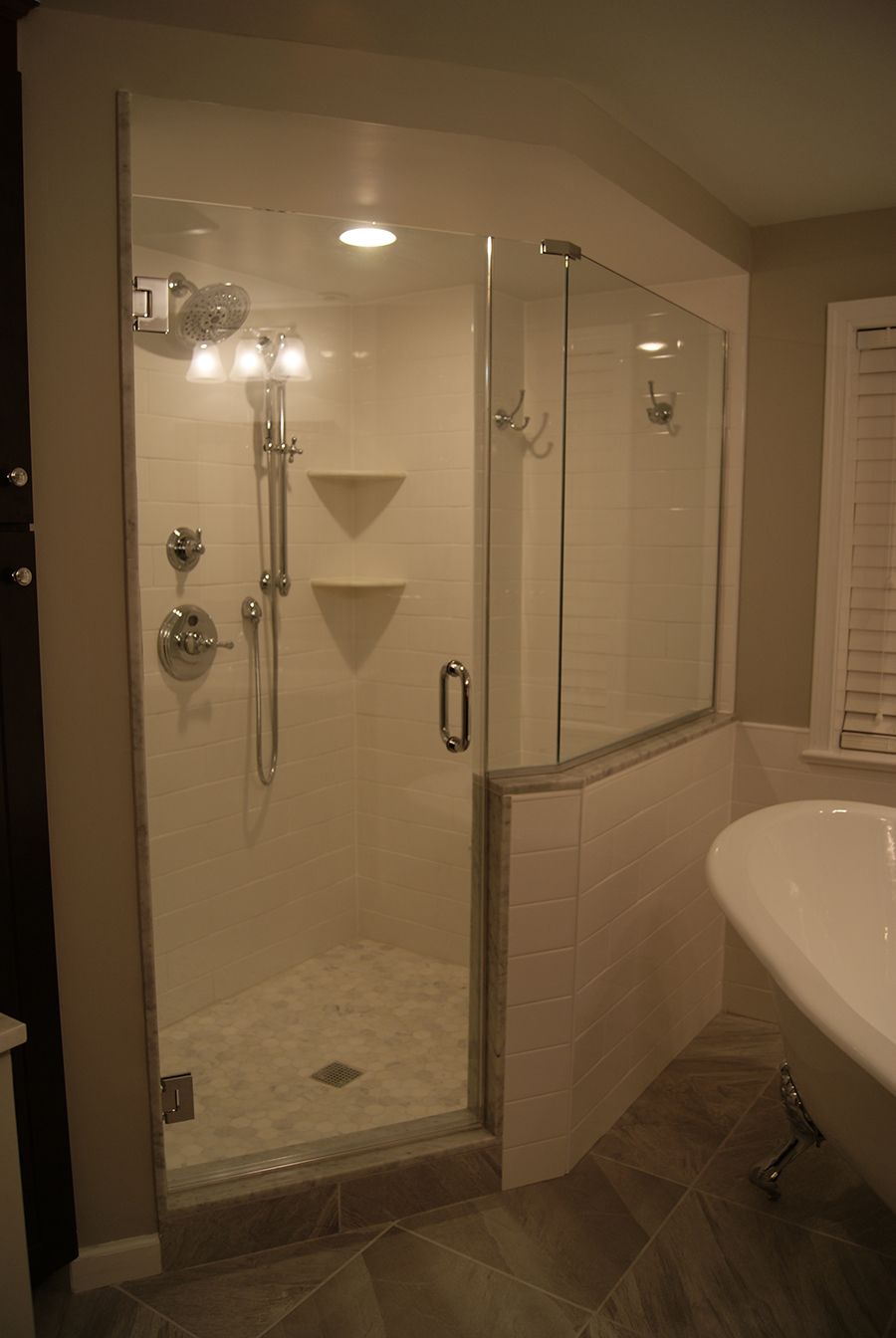 Modern bathroom with glass shower door, white tile, and a freestanding tub.