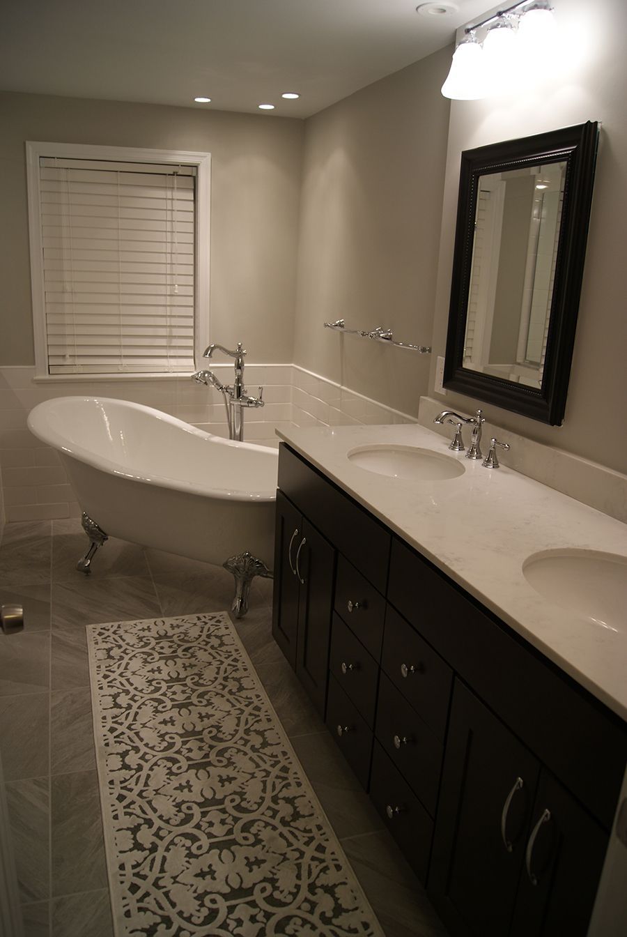 Elegant bathroom with a clawfoot tub, double sink vanity, and patterned rug.