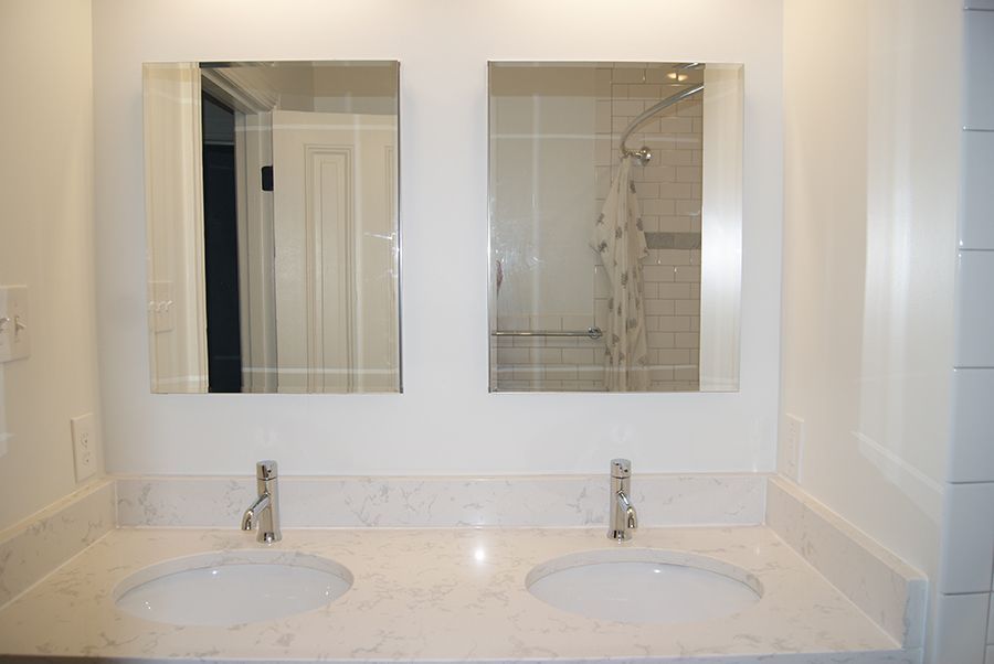 Bathroom with two sinks, two mirrors, and a white countertop.